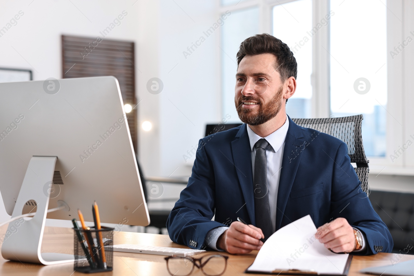 Photo of Man with document working at table in office