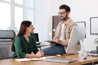 Photo of Colleagues working together at desk in office