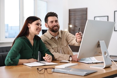 Photo of Colleagues working with computer at desk in office