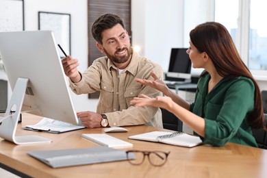 Photo of Colleagues working with computer at desk in office