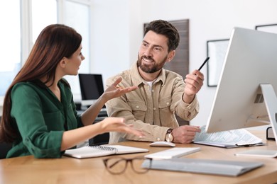 Photo of Colleagues working with computer at desk in office