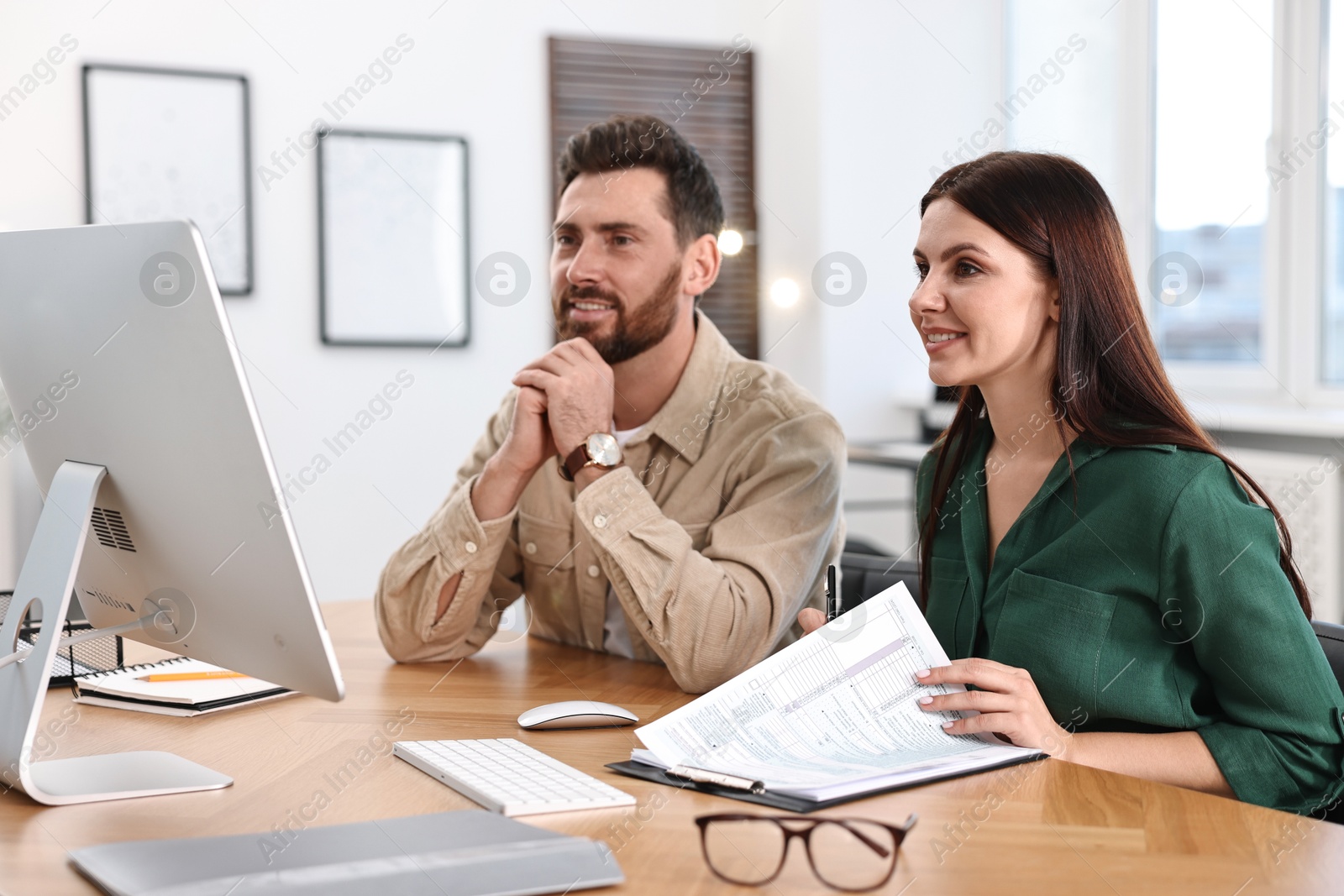 Photo of Colleagues working with computer at desk in office