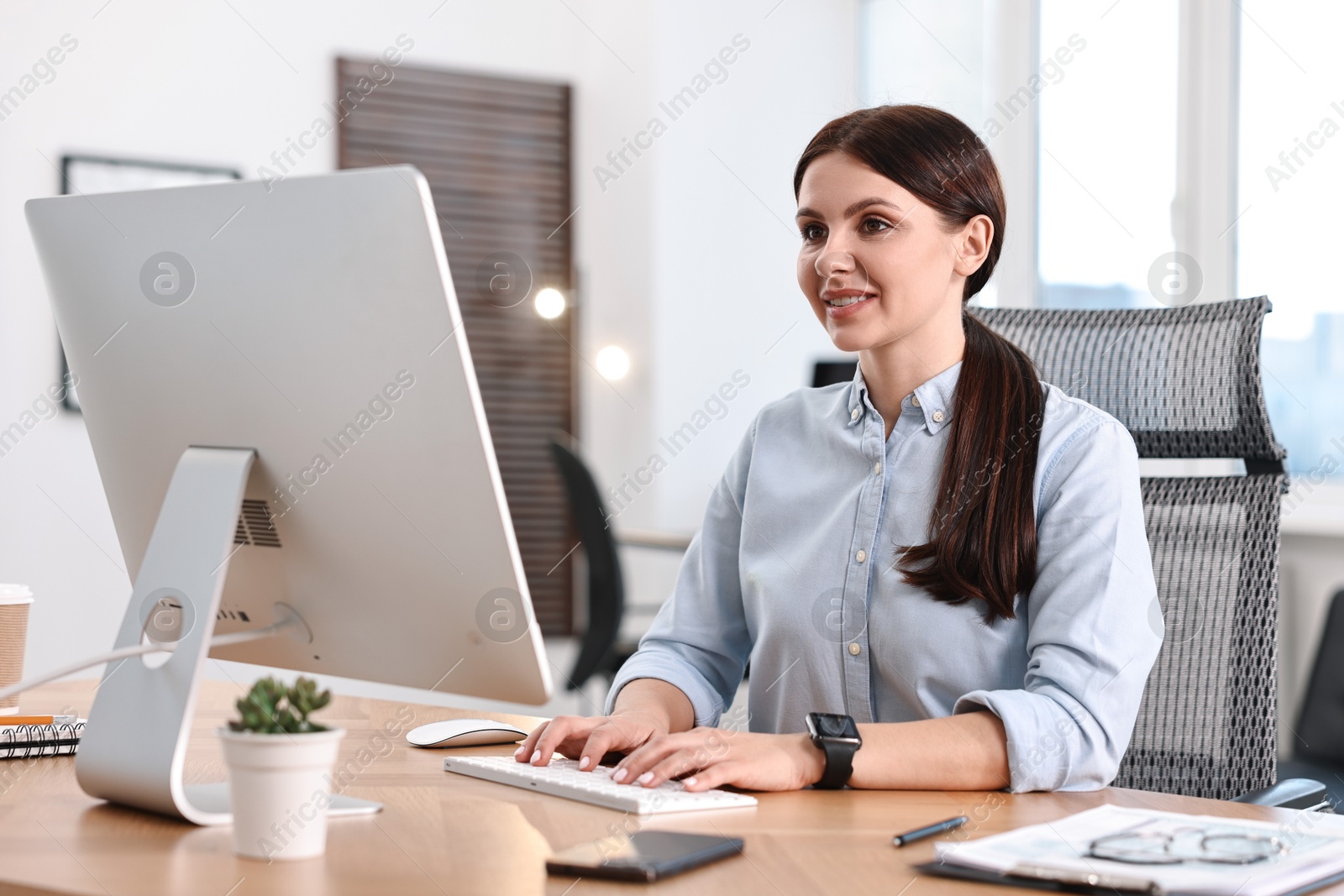 Photo of Woman working on computer at table in office