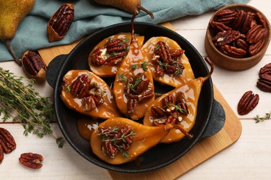 Photo of Delicious pears with caramel sauce, pecan nuts and thyme on wooden table, top view