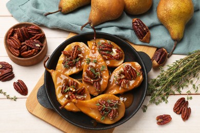 Photo of Delicious pears with caramel sauce, pecan nuts and thyme on wooden table, top view