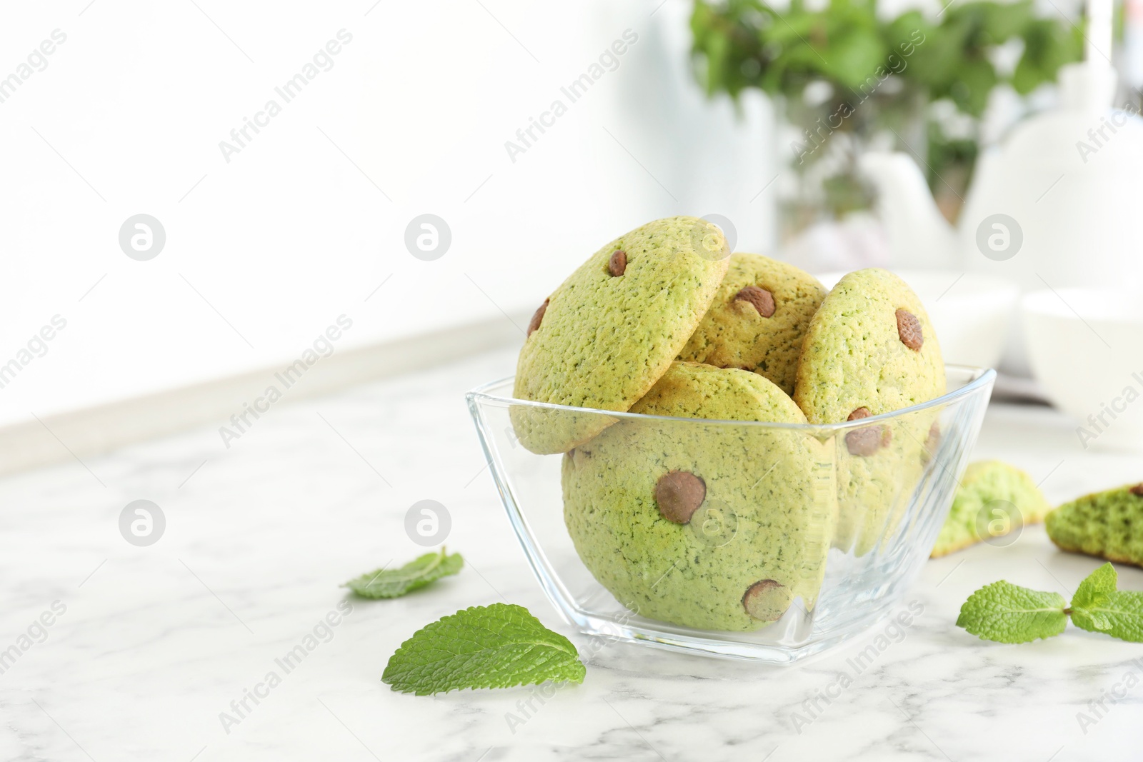 Photo of Delicious mint chocolate chip cookies on white marble table. Space for text