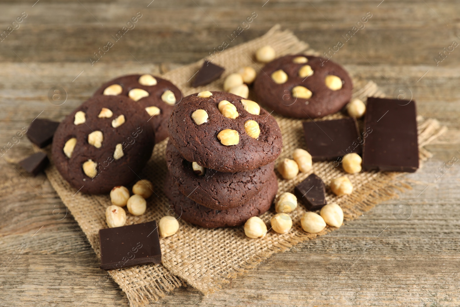 Photo of Tasty chocolate cookies with hazelnuts on wooden table, closeup