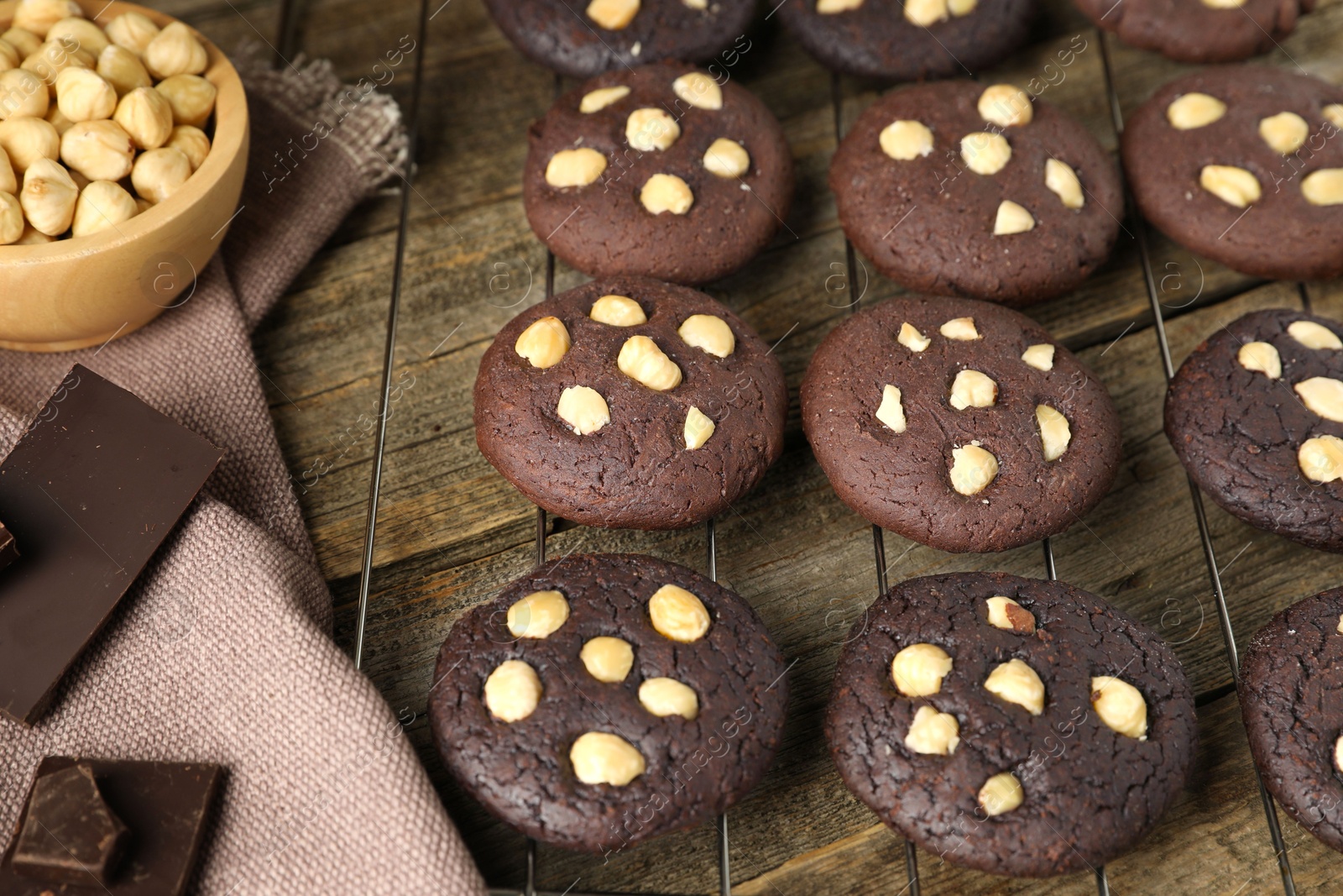 Photo of Tasty chocolate cookies with hazelnuts on wooden table, closeup