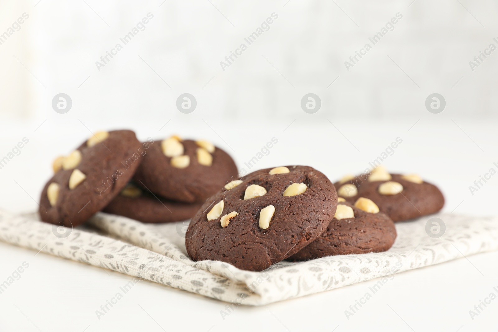 Photo of Tasty chocolate cookies with hazelnuts on white table, closeup