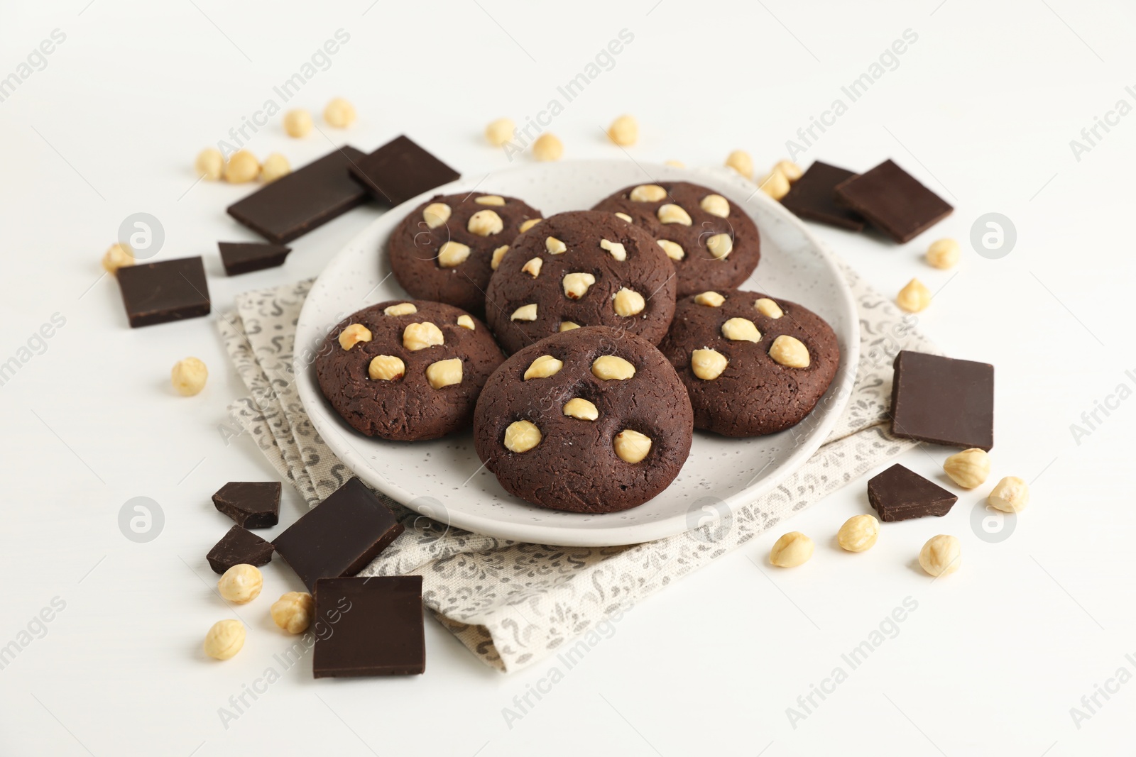 Photo of Tasty chocolate cookies with hazelnuts on white table