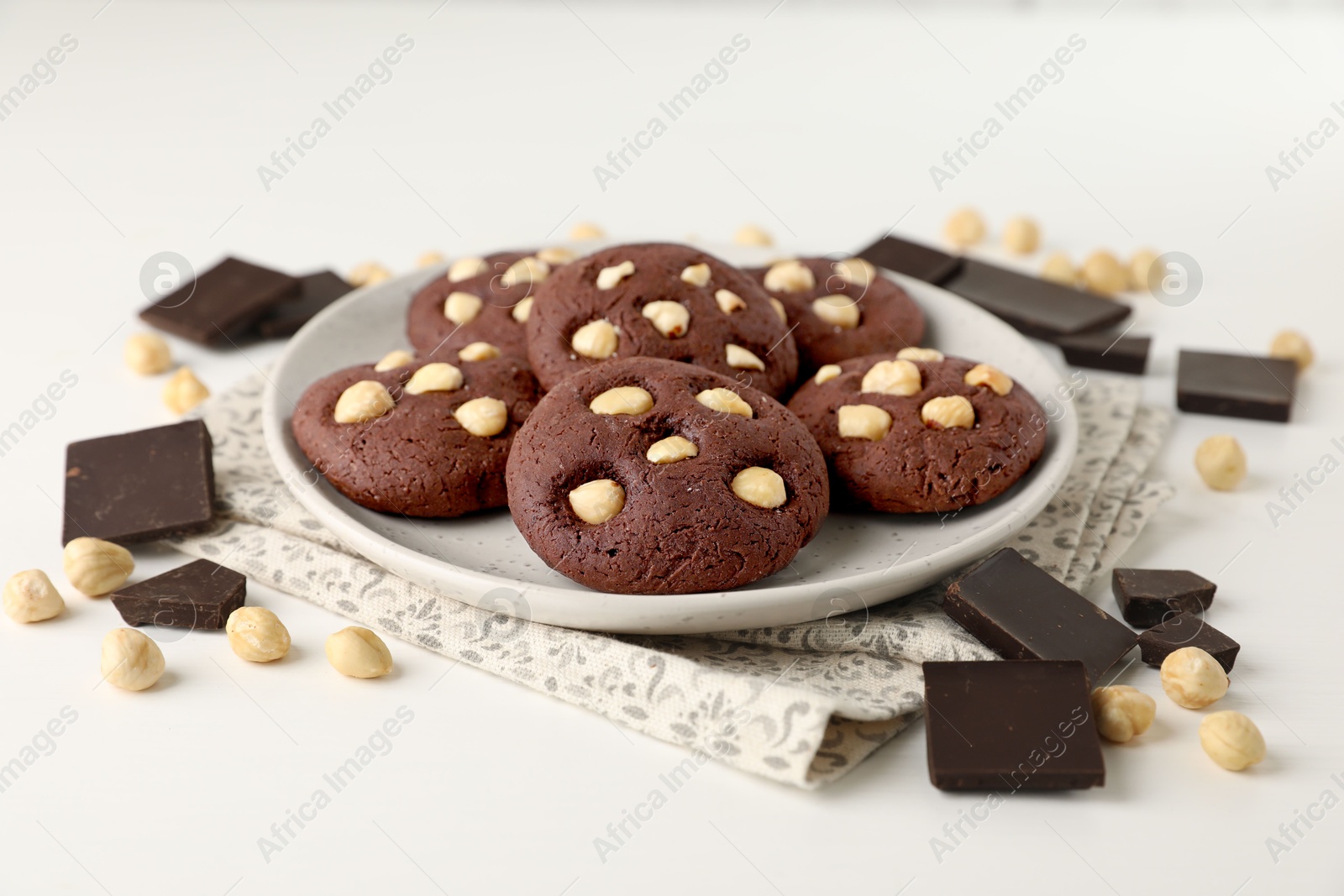 Photo of Tasty chocolate cookies with hazelnuts on white table, closeup