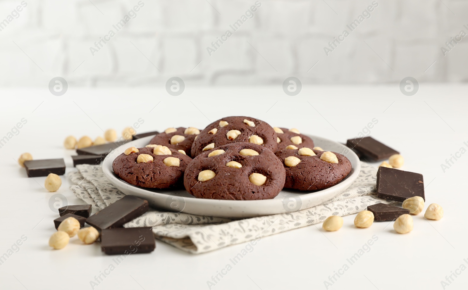 Photo of Tasty chocolate cookies with hazelnuts on white table, closeup