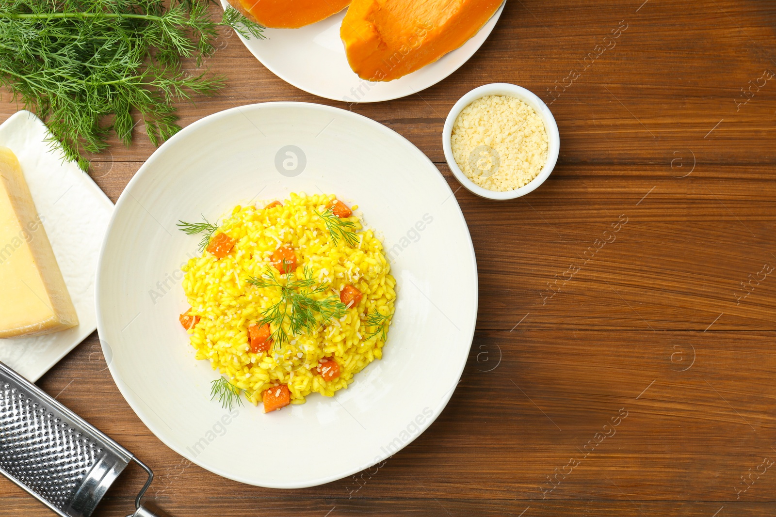 Photo of Delicious pumpkin risotto on wooden table, flat lay