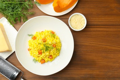Photo of Delicious pumpkin risotto on wooden table, flat lay