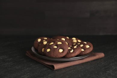 Photo of Tasty chocolate cookies with hazelnuts on black table, closeup