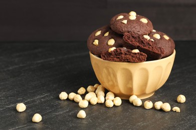 Photo of Tasty chocolate cookies with hazelnuts on black table, space for text