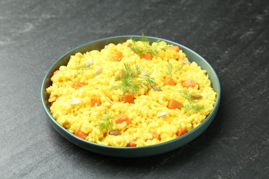 Photo of Delicious pumpkin risotto in bowl on black table, closeup