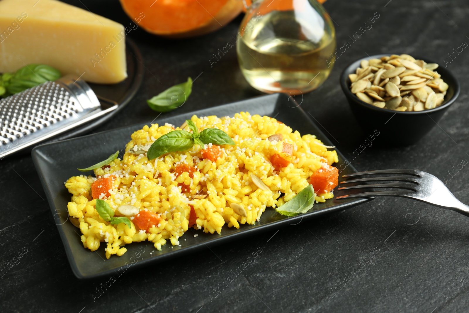 Photo of Delicious pumpkin risotto served on black table, closeup