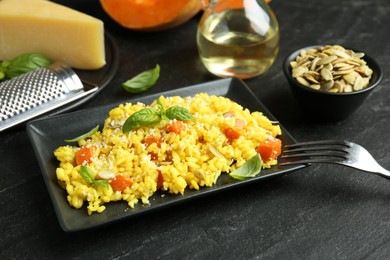 Photo of Delicious pumpkin risotto served on black table, closeup