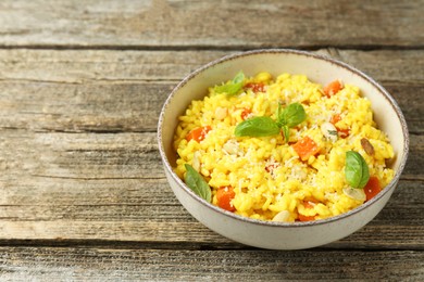 Photo of Delicious pumpkin risotto in bowl on wooden table, closeup. Space for text