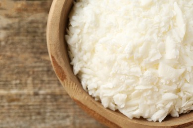 Photo of White soy wax flakes in bowl on wooden table, closeup