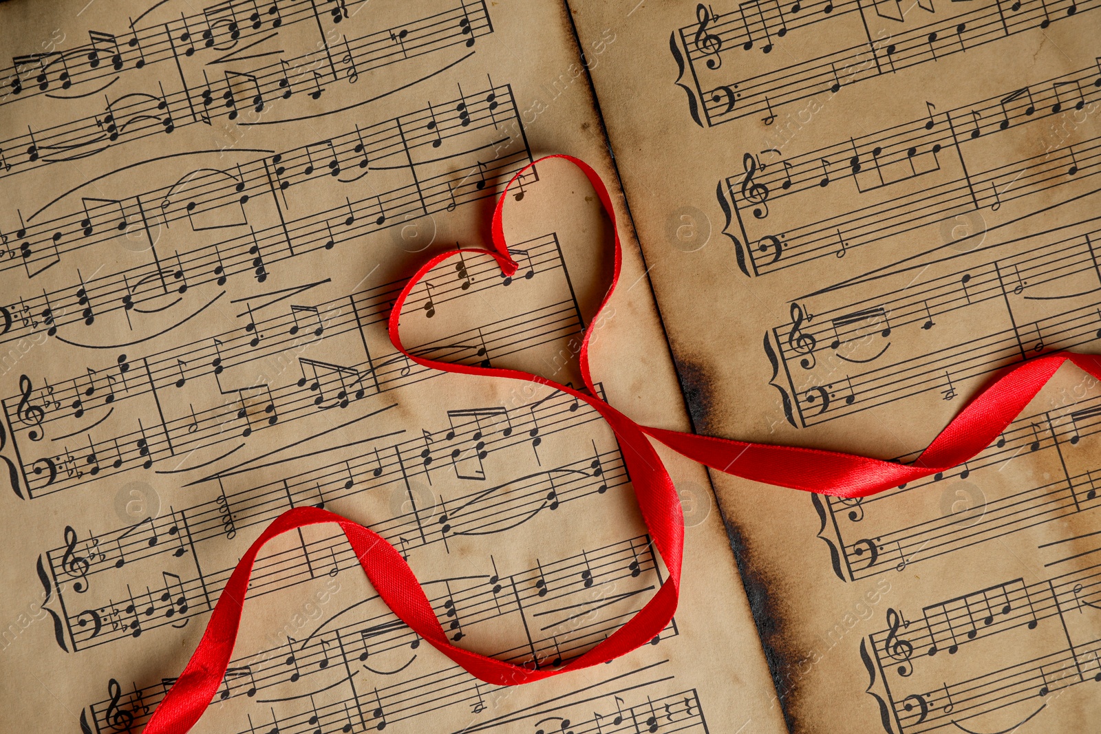 Photo of Heart shaped ribbon on musical notes, top view