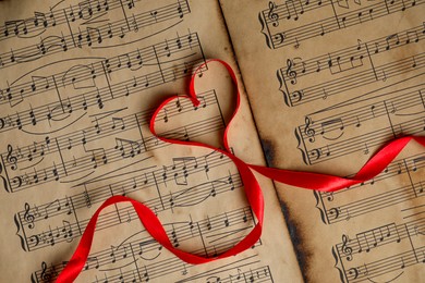 Photo of Heart shaped ribbon on musical notes, top view