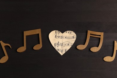 Photo of Paper heart and notes on black wooden table, closeup