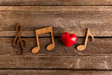 Photo of Red heart figure and notes on wooden table, flat lay