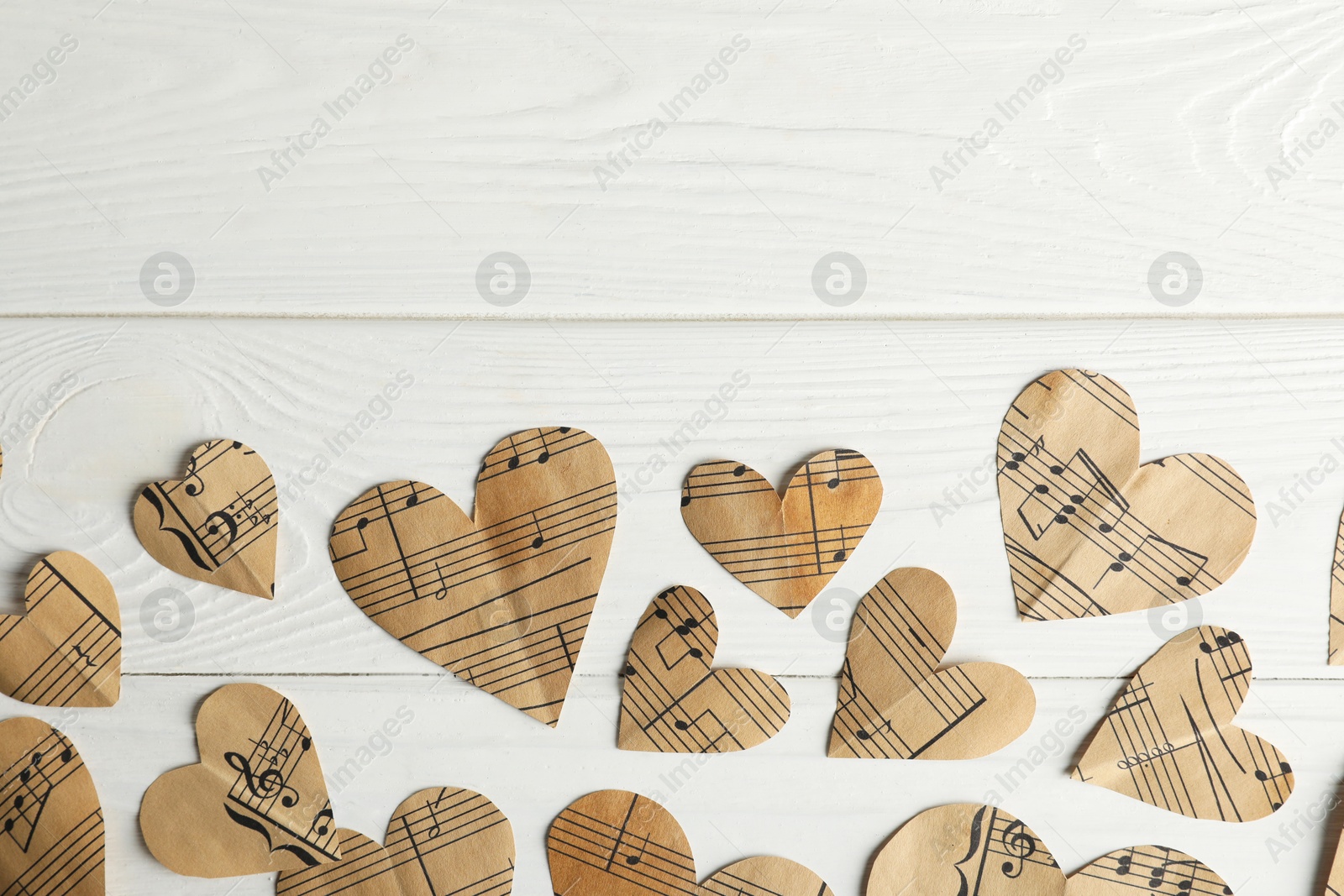 Photo of Paper hearts with notes on white wooden table, flat lay. Space for text