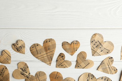 Photo of Paper hearts with notes on white wooden table, flat lay. Space for text