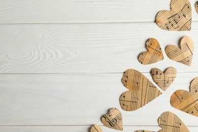 Paper hearts with notes on white wooden table, flat lay. Space for text