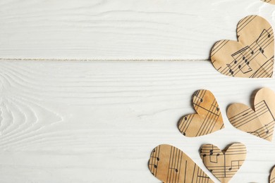 Photo of Paper hearts with notes on white wooden table, flat lay. Space for text