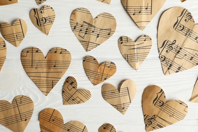 Photo of Paper hearts with notes on white wooden table, flat lay