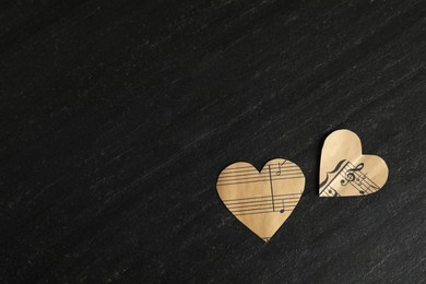 Photo of Paper hearts with notes on black table, flat lay. Space for text