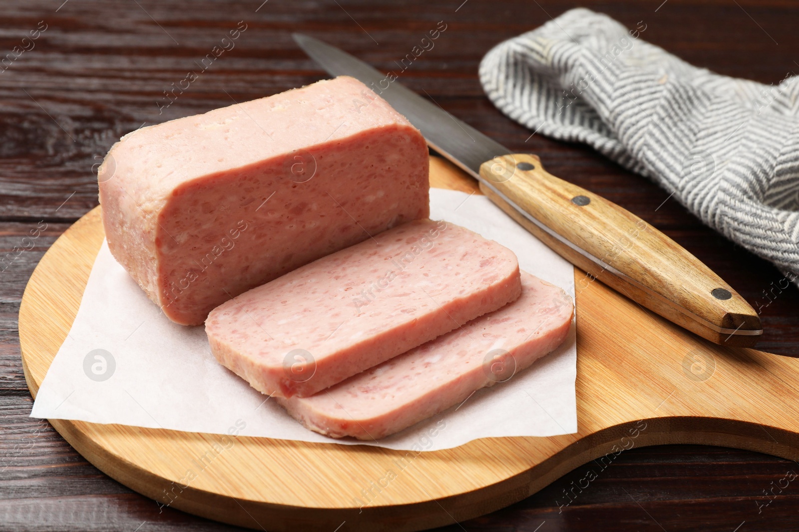 Photo of Tasty canned meat and knife on wooden table, closeup