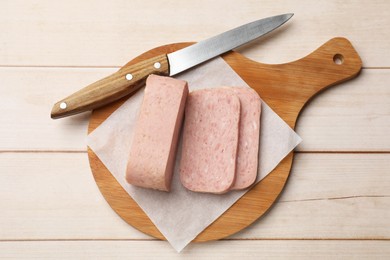 Tasty canned meat and knife on wooden table, top view