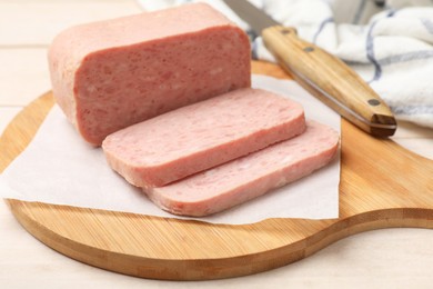 Tasty canned meat and knife on light table, closeup