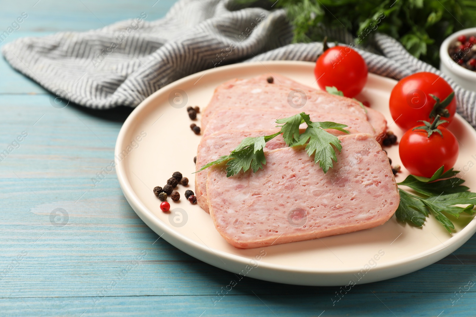 Photo of Pieces of tasty canned meat, parsley, peppercorns and tomatoes on light blue wooden table, closeup