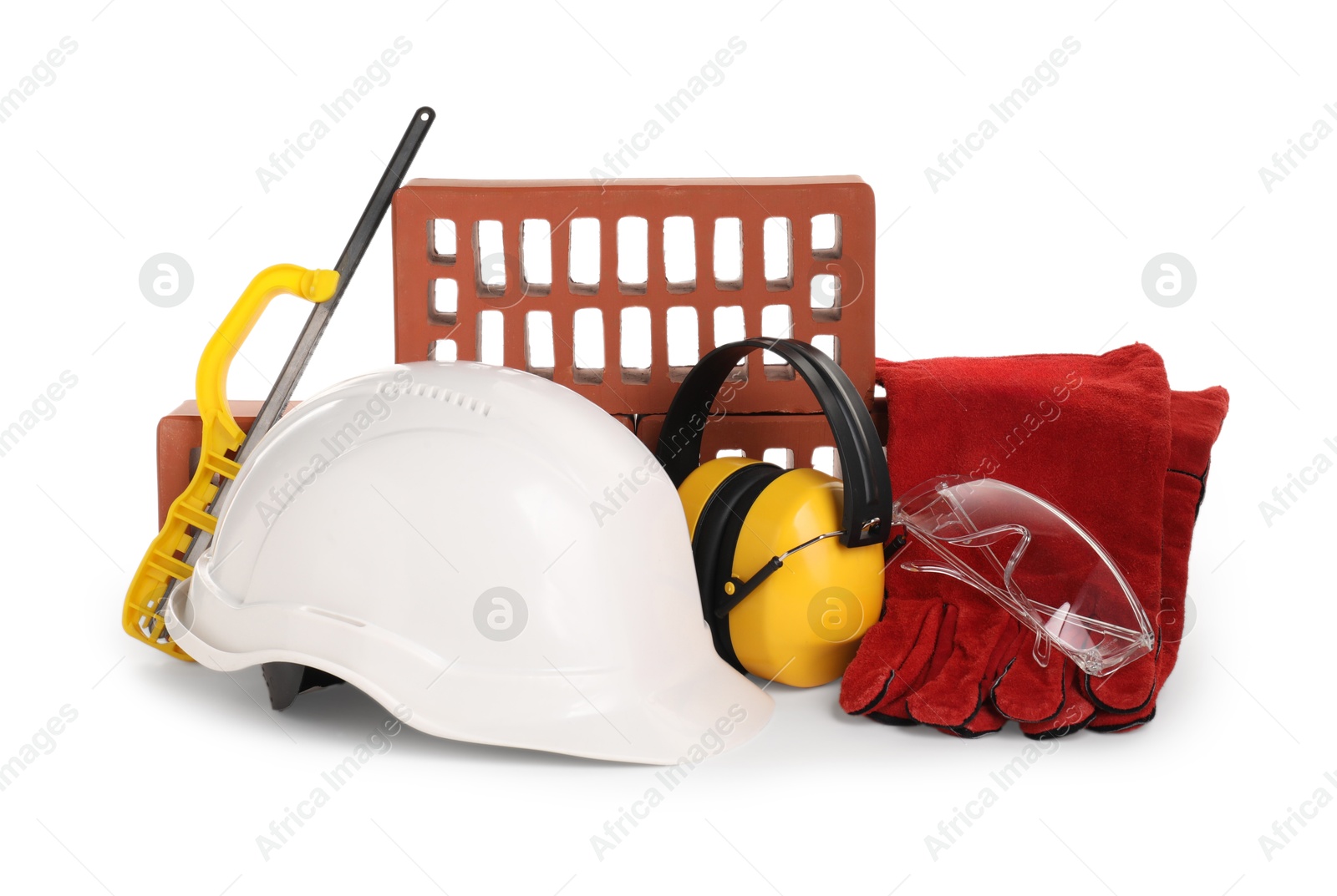 Photo of Safety equipment, red bricks and small hand saw isolated on white. Construction tools and building material