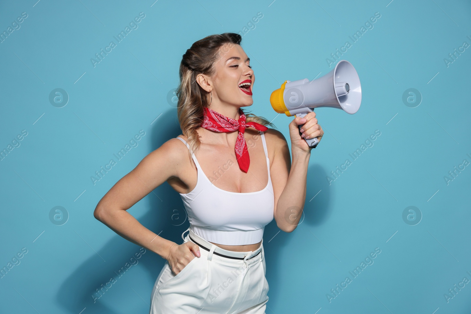 Photo of Excited pin-up woman shouting in megaphone on light blue background