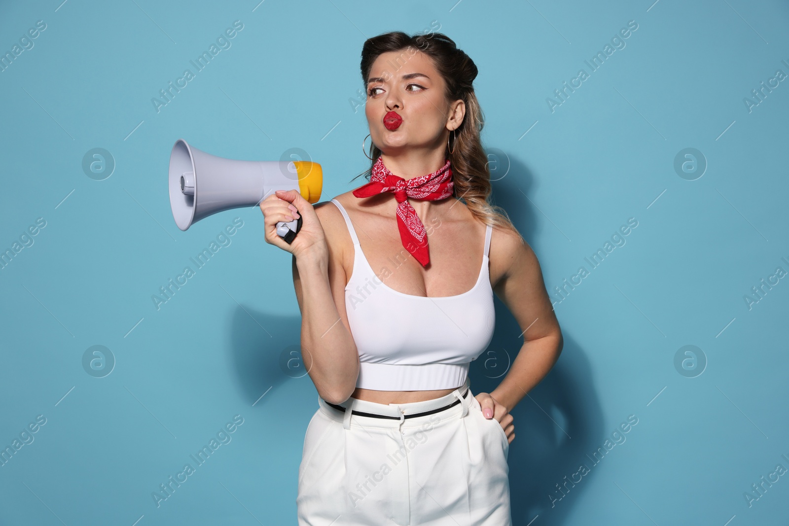 Photo of Attractive pin-up woman with megaphone on light blue background