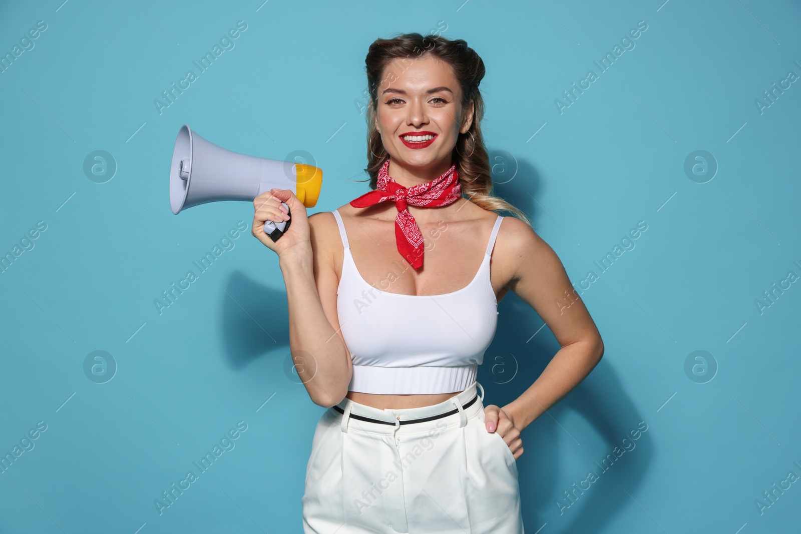 Photo of Happy pin-up woman with megaphone on light blue background