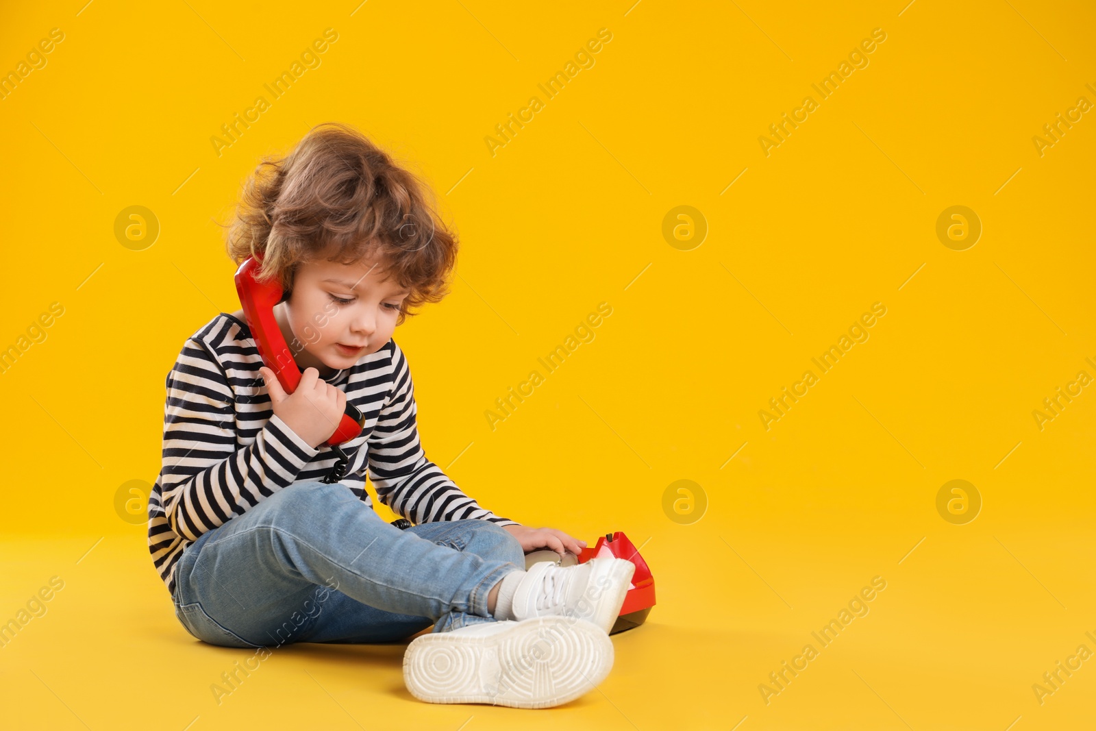 Photo of Cute little boy with telephone on orange background, space for text