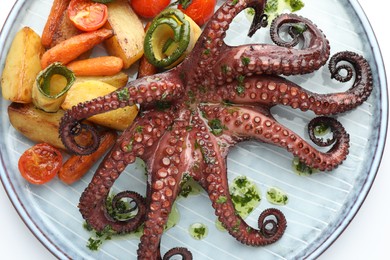 Photo of Fried octopus with herb sauce and vegetables on white background, top view