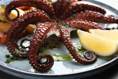 Photo of Fried octopus with herb sauce, lemon and vegetables on table, closeup