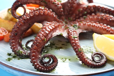 Photo of Fried octopus with herb sauce and lemon on table, closeup