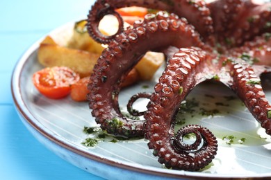 Photo of Fried octopus with herb sauce and vegetables on light blue wooden table, closeup