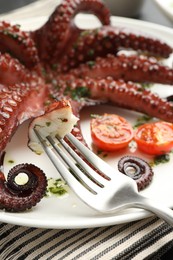 Eating tasty fried octopus with herb sauce at table, closeup