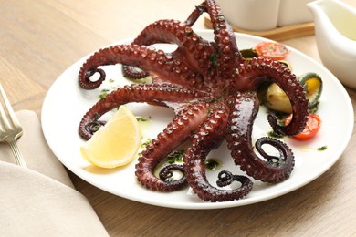 Photo of Fried octopus with herb sauce, lemon and vegetables on wooden table, closeup